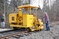 Volunteers operate tie spacer on tracks.