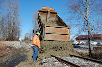 Dump truck drops load of ballast on tracks to repair January flood damage in March 2009