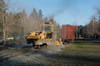Repairs to tracks damaged in January 2009 floods along Railroad Ave with parking log and train in background.