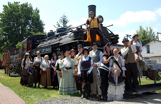 Steam Rats posing with Locomotive 11. People in steam punk wear outside on the grounds of Snoqualmie Depot.