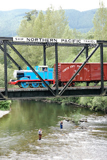 Thomas the Tank Engine with boxcar going over Bridge 25 over the South Fork of the Snoqualmie River with fishermen in the river.