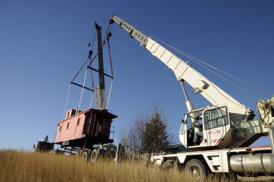 Crane lifting caboose out of field in Montana.