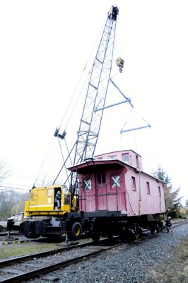 Caboose being lower on to tracks by crane.