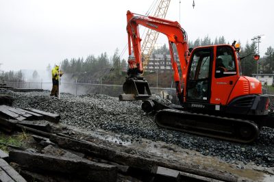 Railworks hyrail excavator at Snoqualmie Falls spreading new ballast; Salish Lodge and Spa is across the river in the distance.