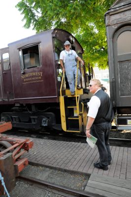 The Engineer and Conductor of the Northwest Railway Museum's excursion train talk before departure from Snoqualmie. The engineer is on the back platform of the diesel, and the conductor is on the platform, looking towards the depot.