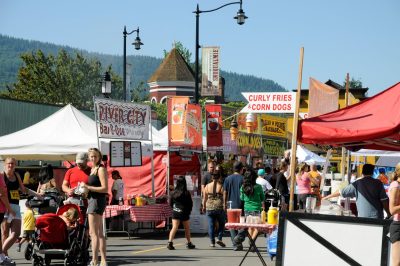 People walk in front of food vendors along King Street during Snoqualmie Railroad Days 2011. The top of the Snoqualmie Depot turret can be seen poking out above the stalls.