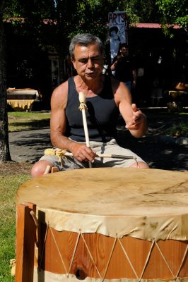 John Mullan, mallet in hand, sits in front of a large hide drum.