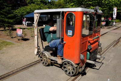 A two-seater orange motor car (or speeder) sits perpendicular on the track at a crossing.