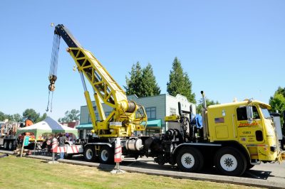 A large yellow semi-truck crane is set up along Railroad Ave in Snoqualime. On the truck cab is the "Swoosh" BNSF logo. BNSF uses this crane for the rerailing of derailed equipment.