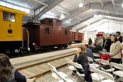 White River Lumber Co caboose #001 and Weyerhaeuser Timber Co. locomotive #1 are pushed into the Train Shed for the opening of the building. Guests watch from the side.