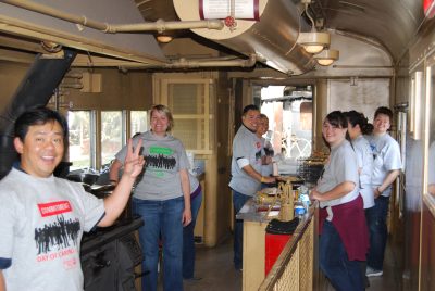 Marriot Hotel volunteers inside the Army Ambulance Kitchen Car smiling at the camera and running kitchen.