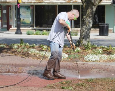 A Microsoft volunteer power washing the brick walkway in front of the Snoqualime depot.