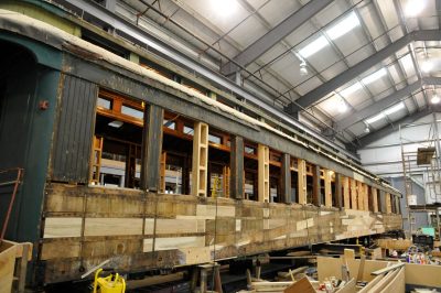 Chapel Car Messenger of Peace in the Conservation and Restoration Shop under repair. One side has the cladding removed, showing the framework with new wood installed.