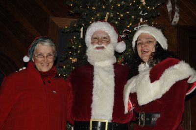 Zoe, Santa, and Mrs. Claus (left to right) smile in front of a Christmas tree in the Snoqualmie Depot