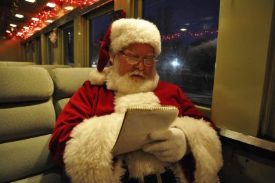 Santa reclines in Spokane, Portland & Seattle coach 276. In his hand is a notepad, which he is studying.