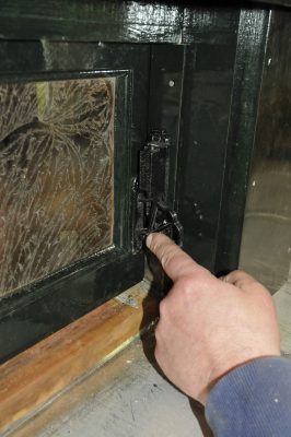 A repaired and reinstalled clearstory window on Messenger of Peace. A finger points to the metal mechanism of the window.