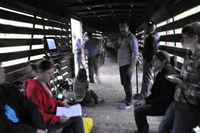 Actors and crew ride inside NP Stock Car 83296 during filming along the Snoqualmie Valley Railroad. Director Robinson Devor is seen looking at the camera, and actor Michael Pitt as hobo Jack Black can been seen at the back of the car.