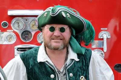 A Seafair Pirate in green ensemble, with the Snoqualmie Fire Truck as a background.