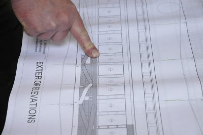 An Exterior Elevation drawing for the left side of Messenger of Peace is shown. A finger points out a window.