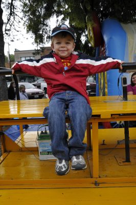 A young visitor sits on the speeder trailer at DOWT 2012. The bouncy house is visible behind.