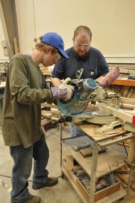 A 2012 RailCamper uses a table saw in the CRW under the guidance of Dan C.