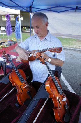 A vendor holds a refurbished string instrument while others rest in their cases before him during Snoqualmie Railroad Days 2012