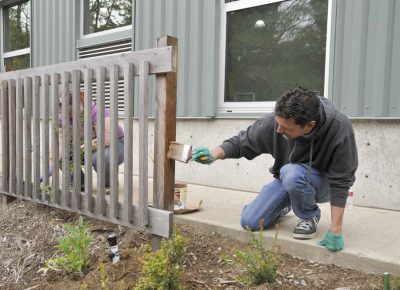 Day of Caring 2012 volunteers stain a fence at the Train Shed