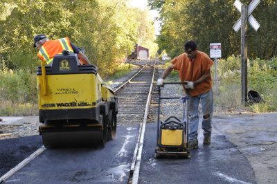 Asphalt By George crew compacting asphalt at Stone Quarry Rd. crossing. CRW is visible in distance.