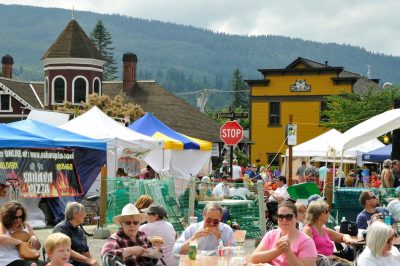 Food vendors are set up along King St. during Snoqualmie Railroad Days 2014. People eat food in the foreground, while the Snoqualmie Depot and IOOF Hall rest in the background.