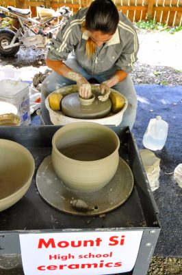 Mount Si High ceramics student demonstrates pot making with formed pots in the foreground.