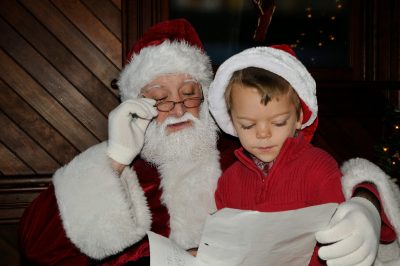 A young visitor sits on Santa's lap while both review his Christmas List during Santa Train 2014.