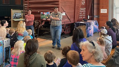 An educator reads a story to a group of families.