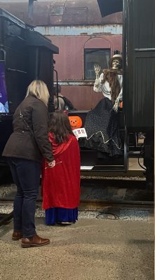 A mother and daughter are greeted by a friendly skeleton on Messenger of Peace during a scavenger hunt at Halloween Train 2023