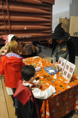 Young guests make a mini scarecrow under the watchful eye of a volunteer.