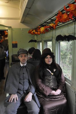 Costumed guests ride aboard the train with fall leaves and bats decorating the train.