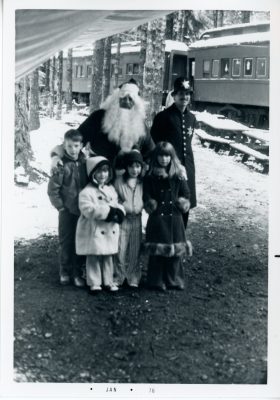 Santa and a Keystone Cop pose for a photo with young kids during Santa Train in 1975