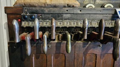 A series of levers set into a wooden frame. Numbers are above each handle from left to right, though not every number has a handle.