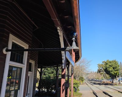 The train order board at Snoqualmie Depot in the  "Proceed" aspect as seen from the platform.  The board is parallel to the tracks, and the green lights are displayed.