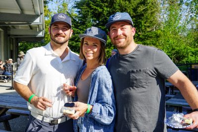 Two men and a women pose outside for a photo.