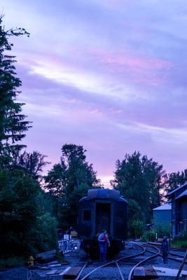 Train crew talks under an indigo and red sky.