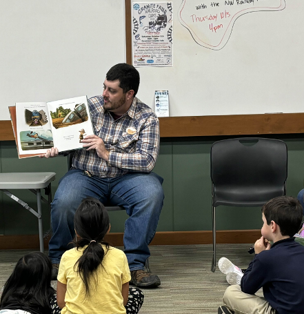 A Museum educator reading a book to some children on a visit to the Granite Falls Library.