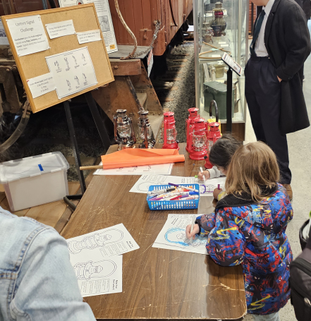 Two young students learn about lantern signals while coloring their own lanterns.