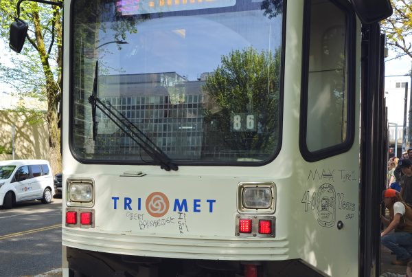 Portland's TriMet MAX Type 1 LRV 124 rests in the shade at Holladay Park. Farewell messages are written on it, with visitors write more on its sides.