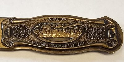 A close up of the handle of a Northern Pacific Railway letter opener promoting their "Great Big Baked Potato". NRM Artifact 2025.002.002
